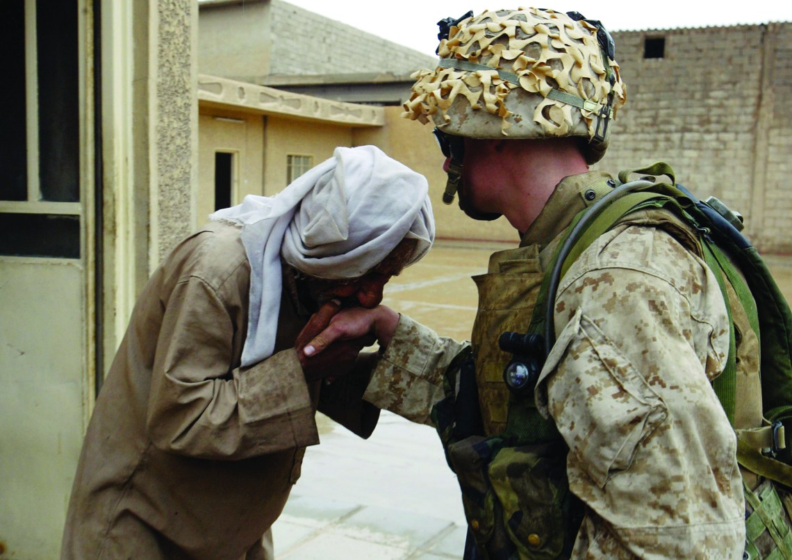 An Iraqi civilian kisses the hand of U.S. Marine Cpl. Joseph Sharp from Peoria, Ill., after Marines from the 1st Battalion 5th Marines gave him a supply of food and water in Fallujah, Iraq, Monday, April 19, 2004. (AP Photo/John Moore)