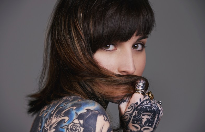 A cropped studio portrait of a beautiful tattooed young woman