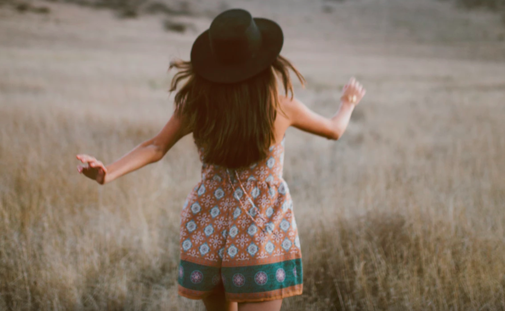 Girl with fedora walking in field