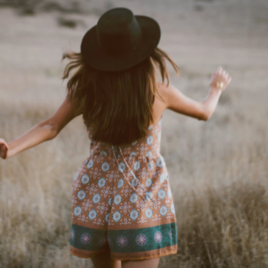 Girl with fedora walking in field