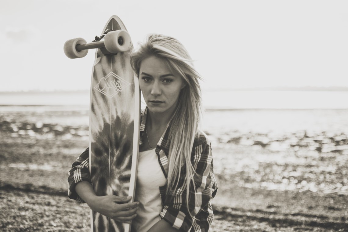Woman with skateboard on beach