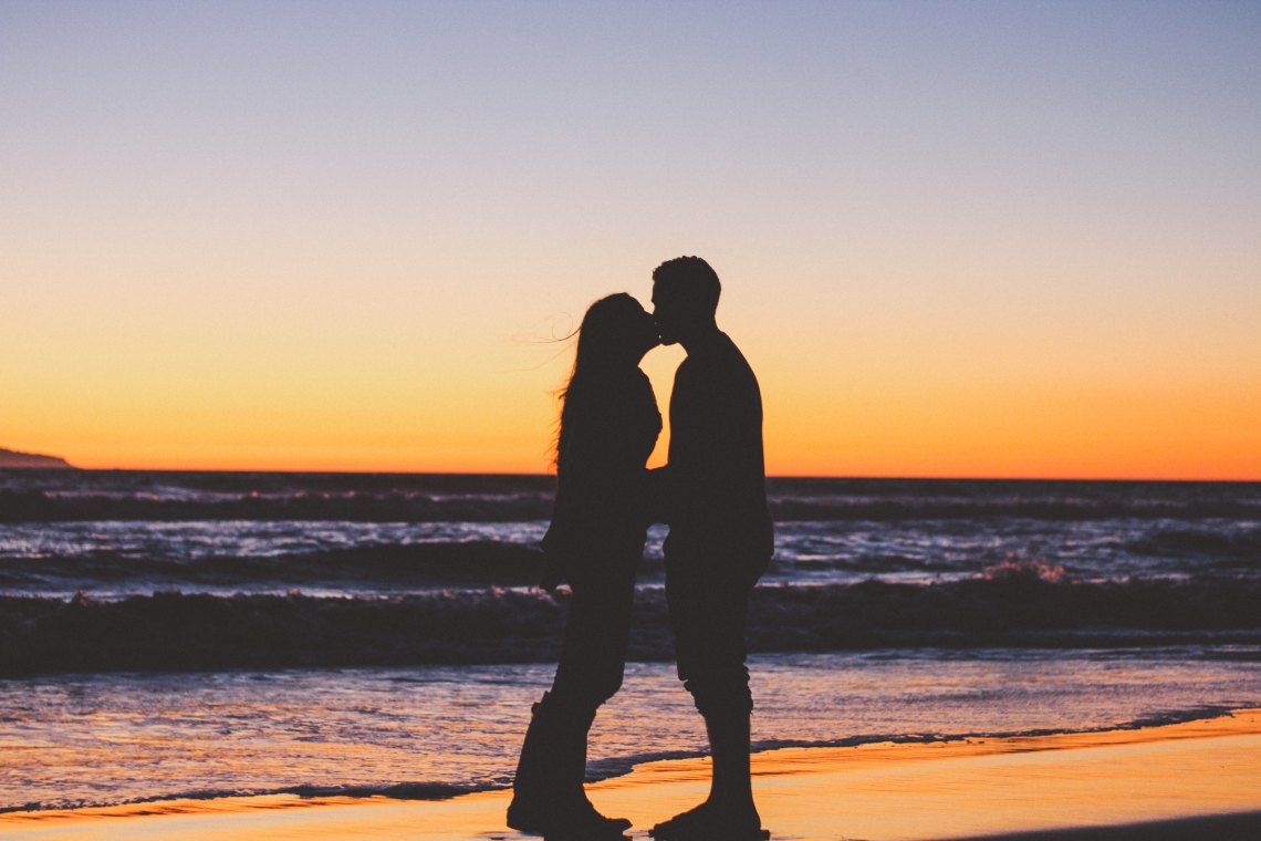 Couple silhouette kissing on beach sunset