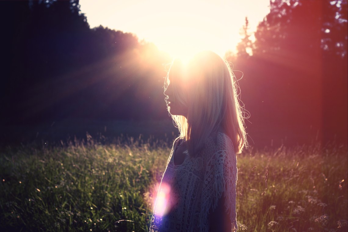 Silhouette blonde woman in front of sun