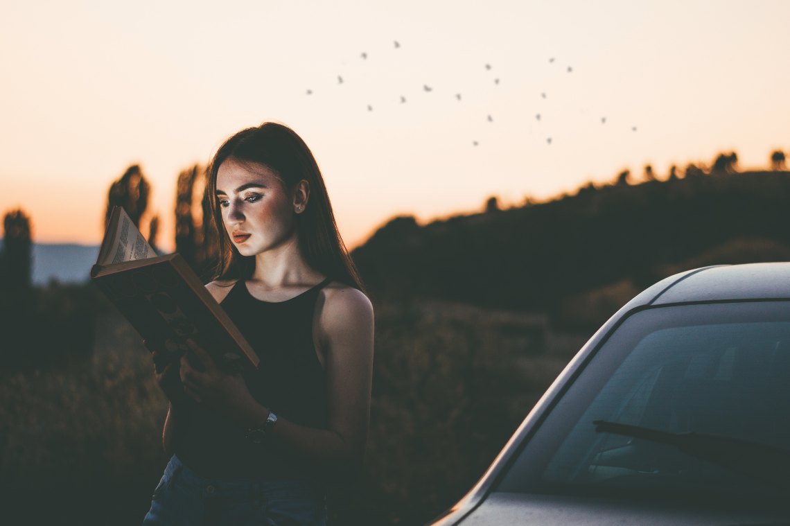 Young woman reading book in front of susnet