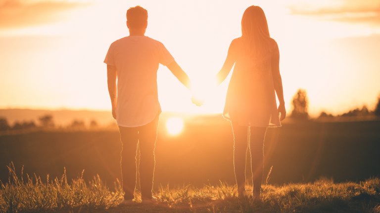Couple holding hands in front of sunset