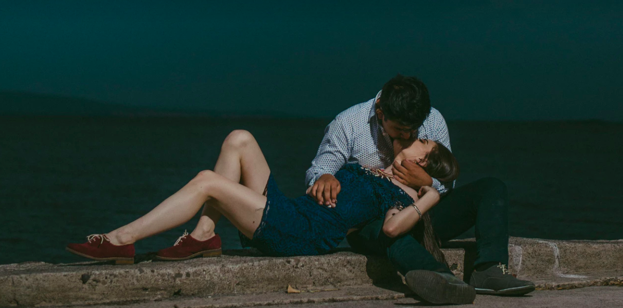 Couple kissing in front of dark lake