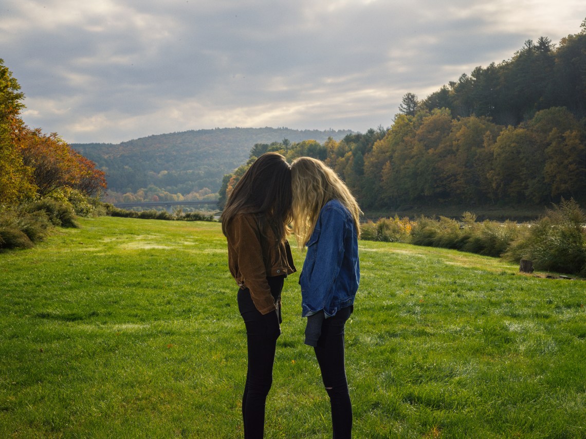 Two girls stand side-by-side in a field