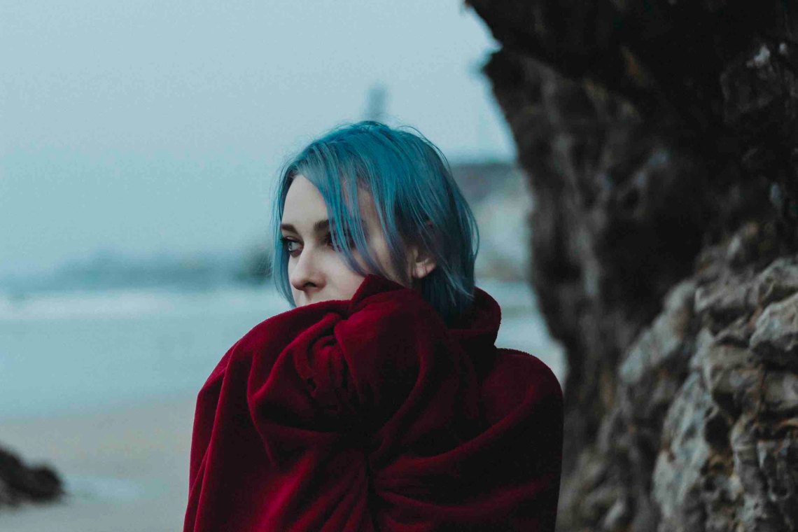 woman standing on beach with blue hair