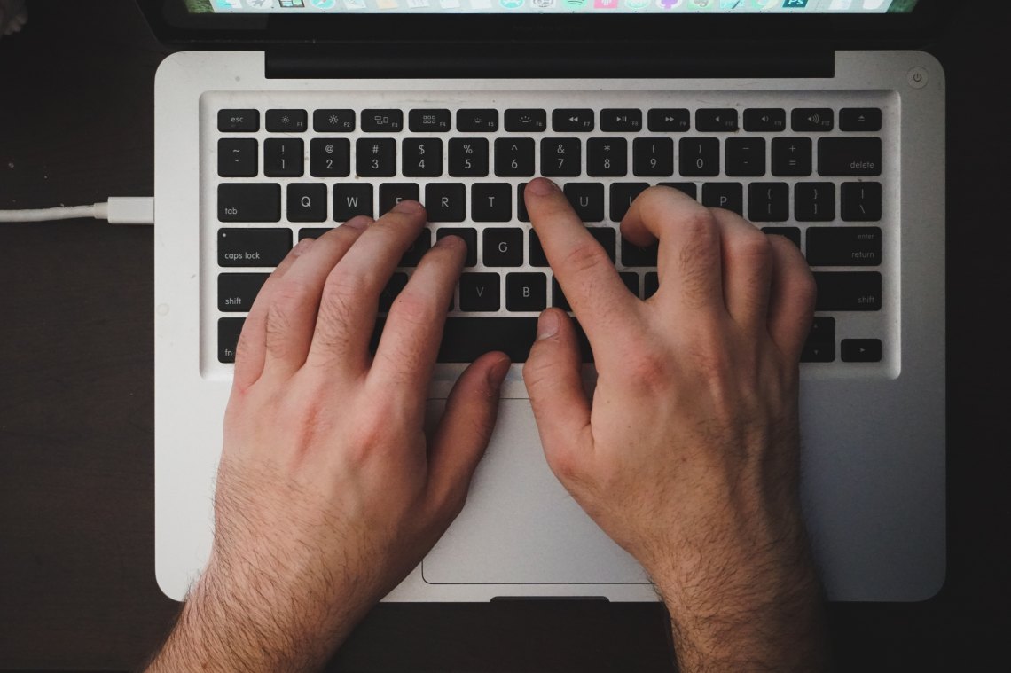 A person types at their macbook