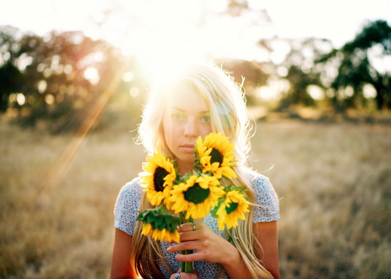 Blonde girl holding sunflowers in meadow
