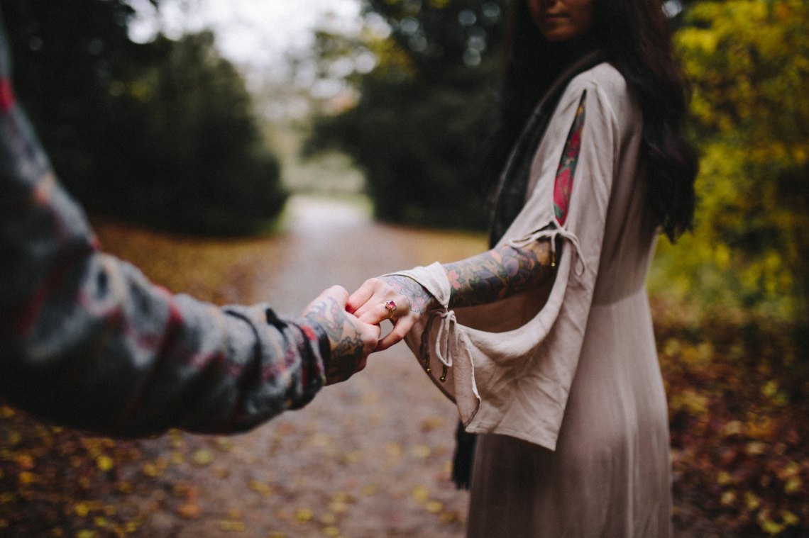 tattooed woman holding man's hand