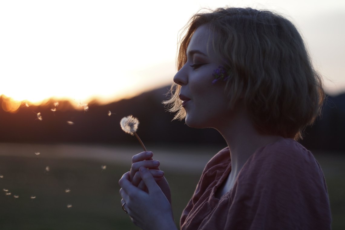 Girl blowing flower in field