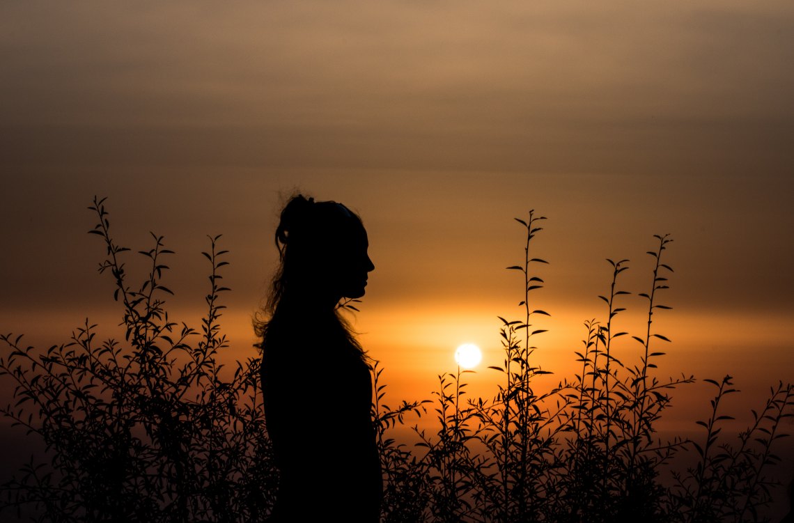 silhouette of woman in front of sunset