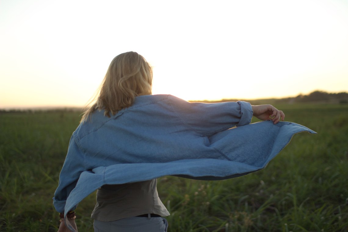 woman standing in field at sunset