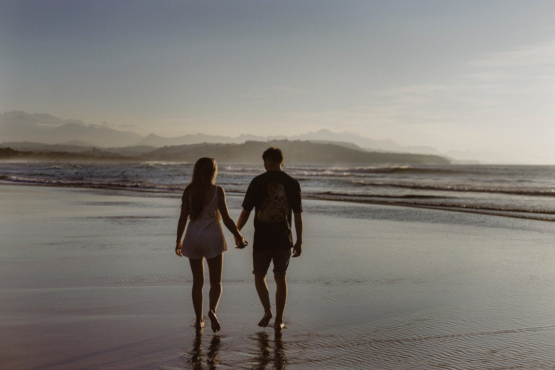 couple walks along the beach holding hands