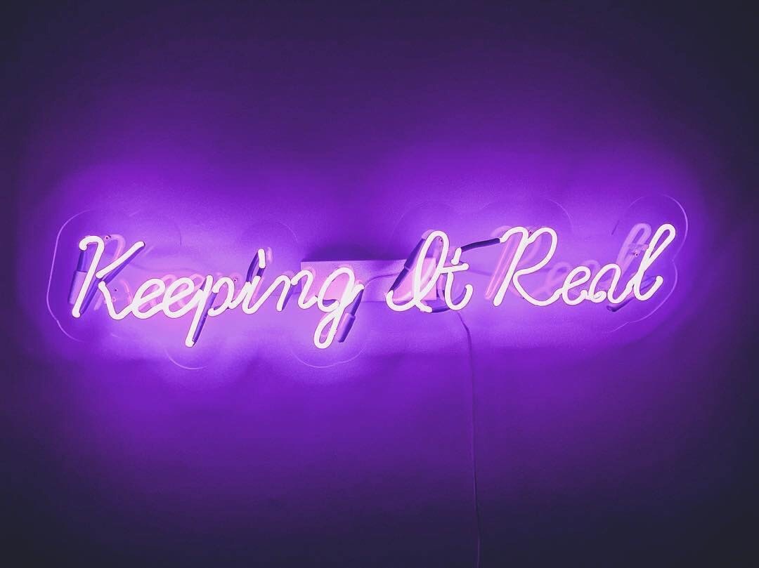 Purple neon sign that says "keeping it real"