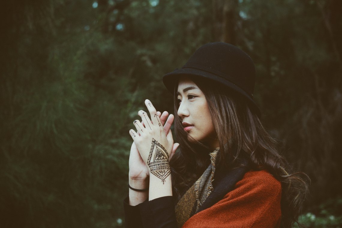 woman in hat with hands clasped
