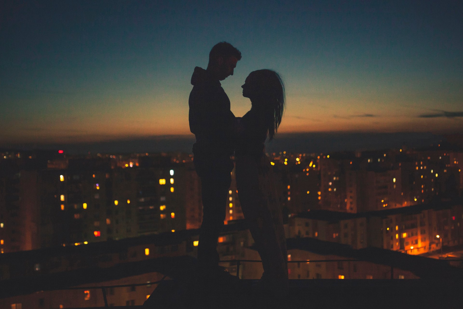 a man and woman embrace in the sunset over the city