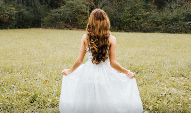Girl in white dress in green field