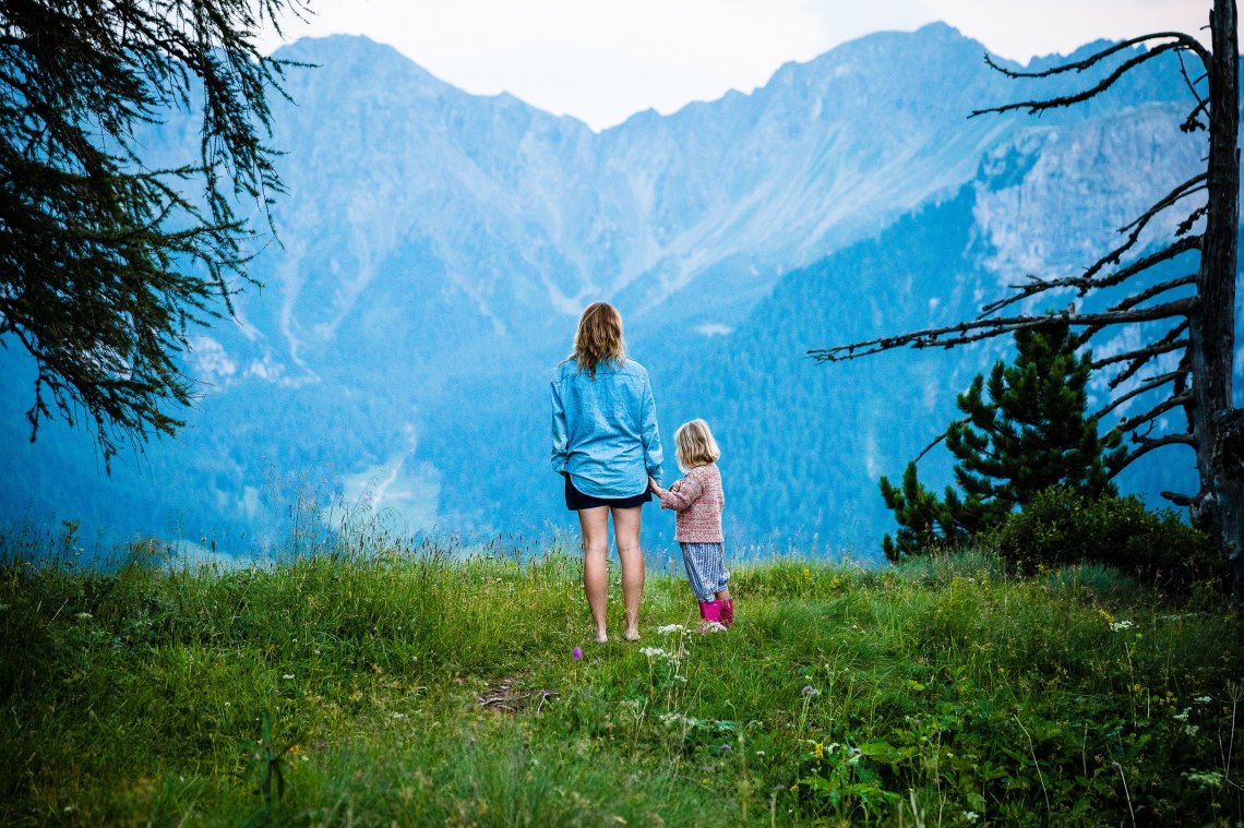 a mother and a daughter standing in front of a mountain