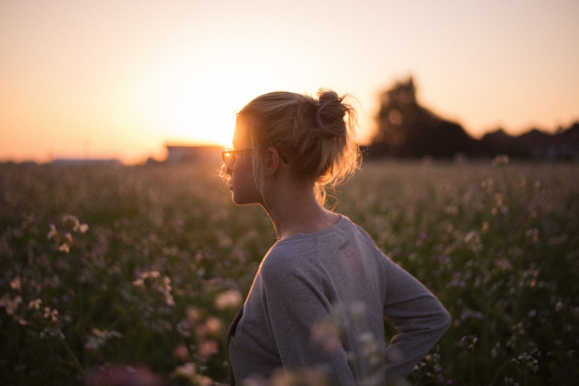Blonde woman standing in front of sunset