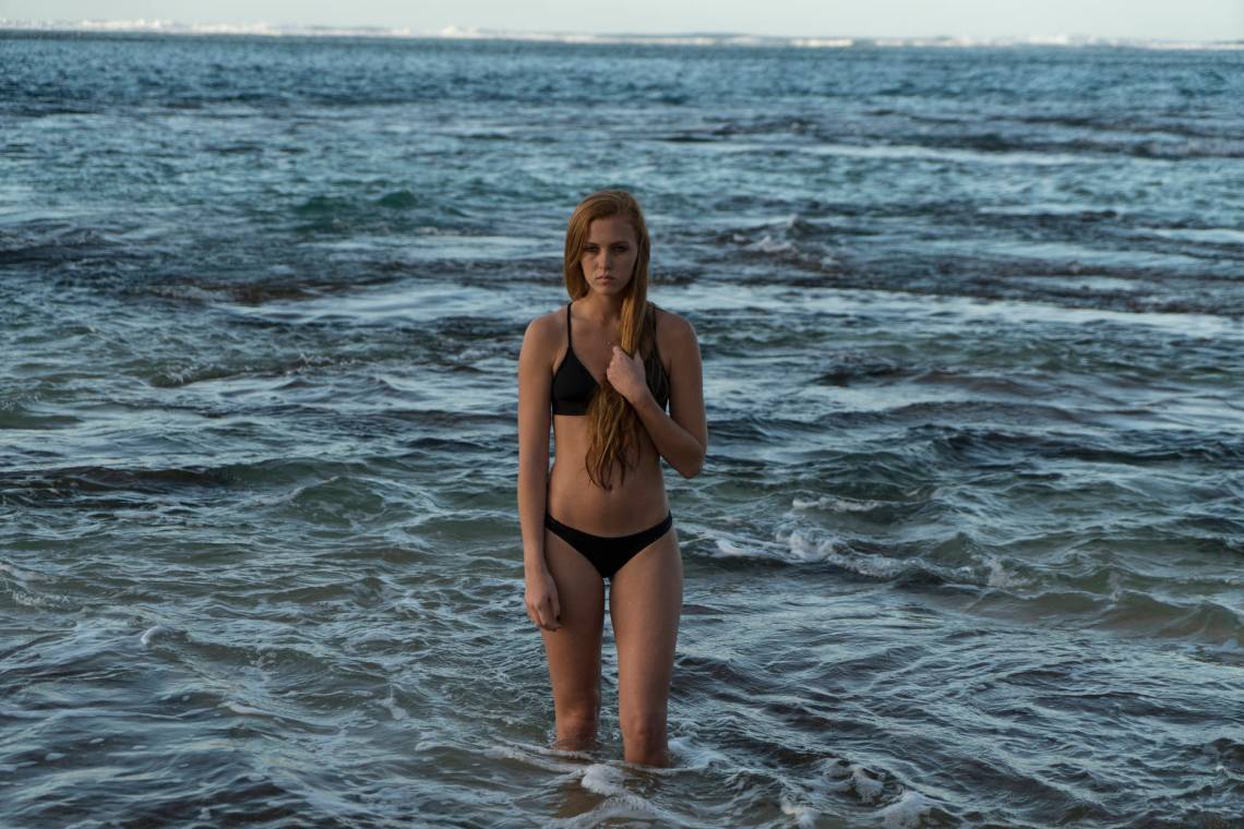 woman stands in the ocean sadly