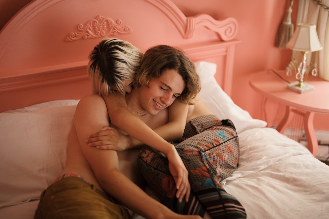 A couple snuggles together in bed, looking cozy