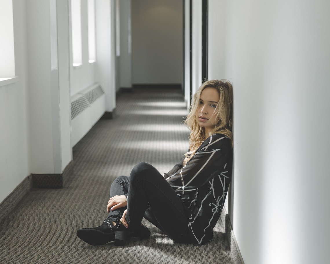 blonde woman dressed in black sitting on floor