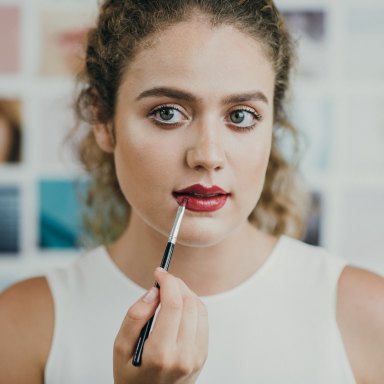woman putting on lipstick