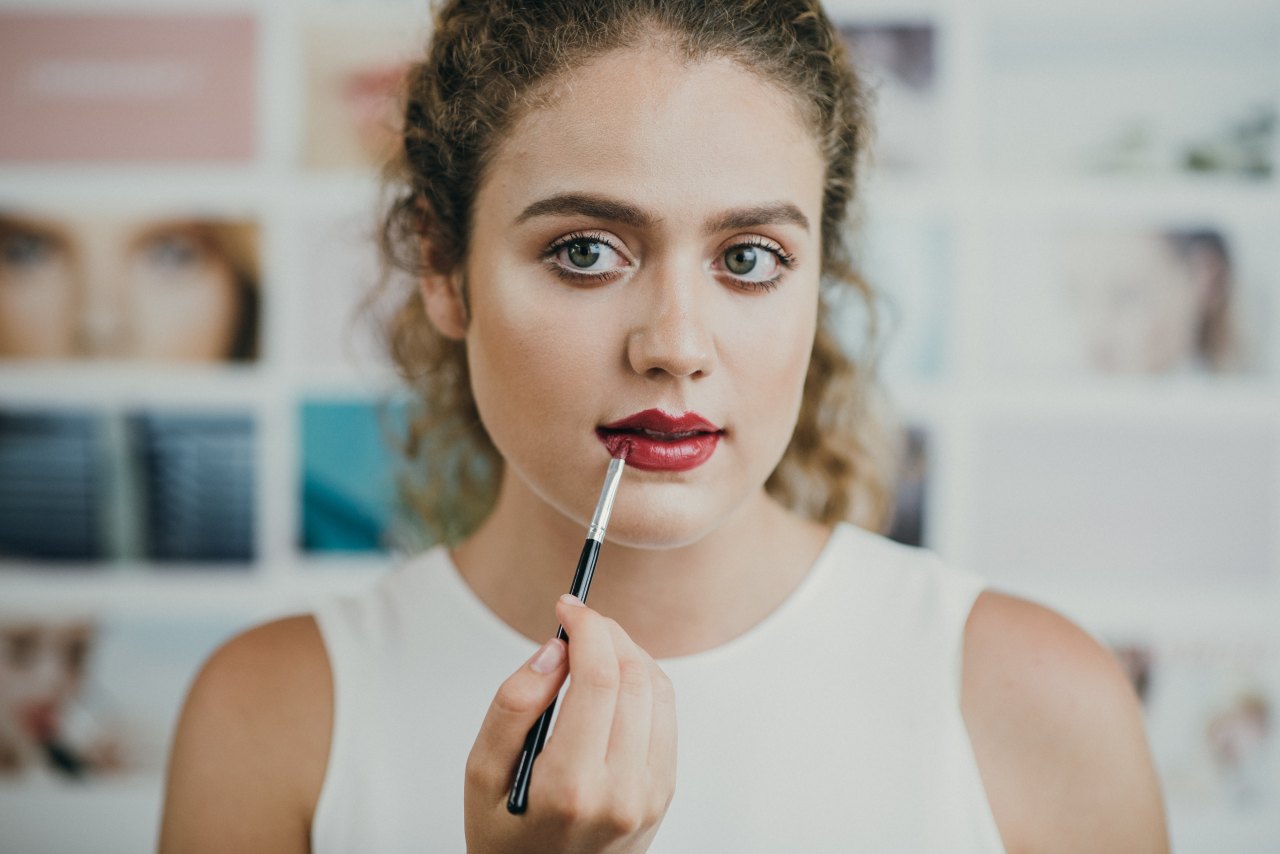 woman putting on lipstick