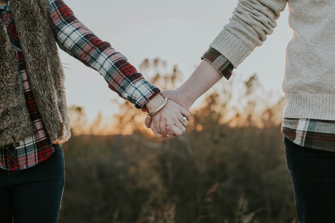 a couple holding hands in a field