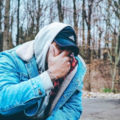 guy in jean jacket covering his face