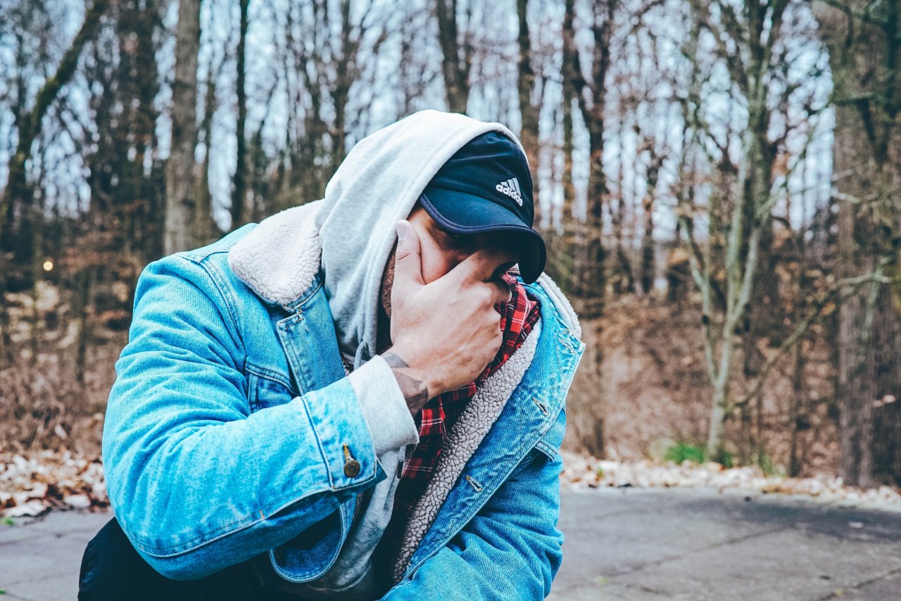 guy in jean jacket covering his face