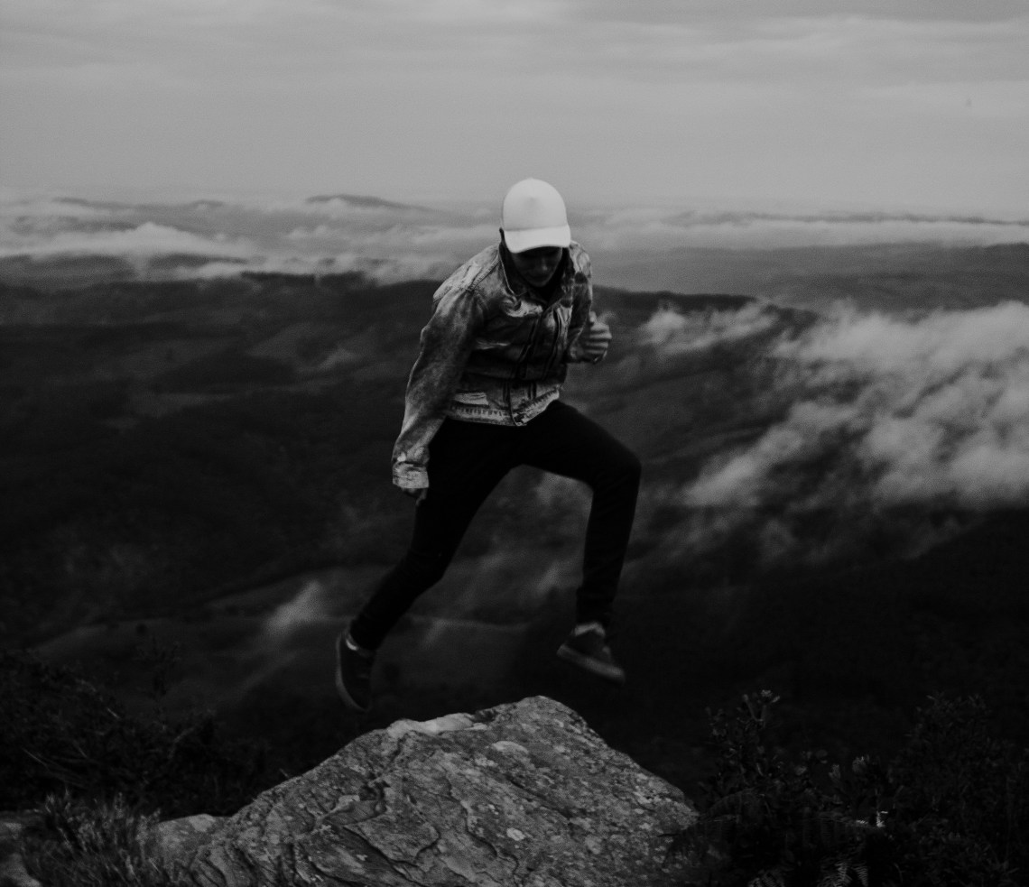 person jumping across mountains, ambition, believe in ambition