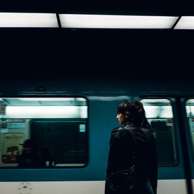 woman stands at a train station looking out