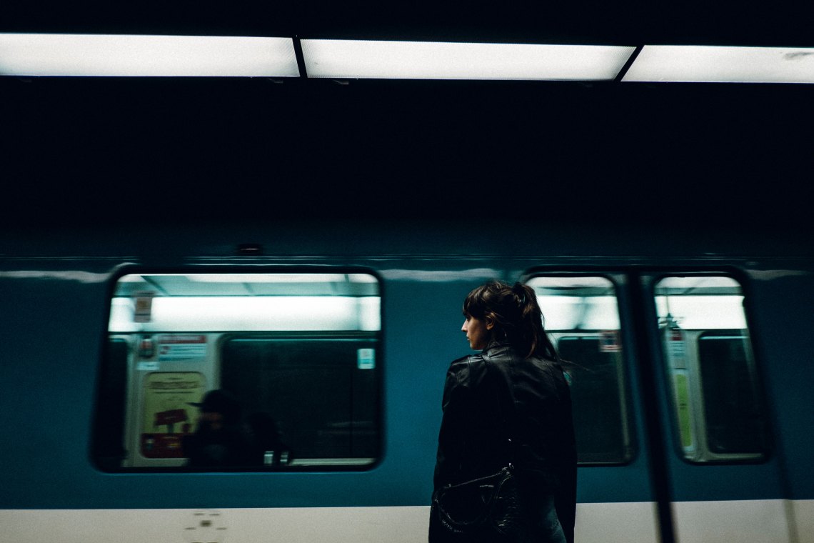 woman stands at a train station looking out