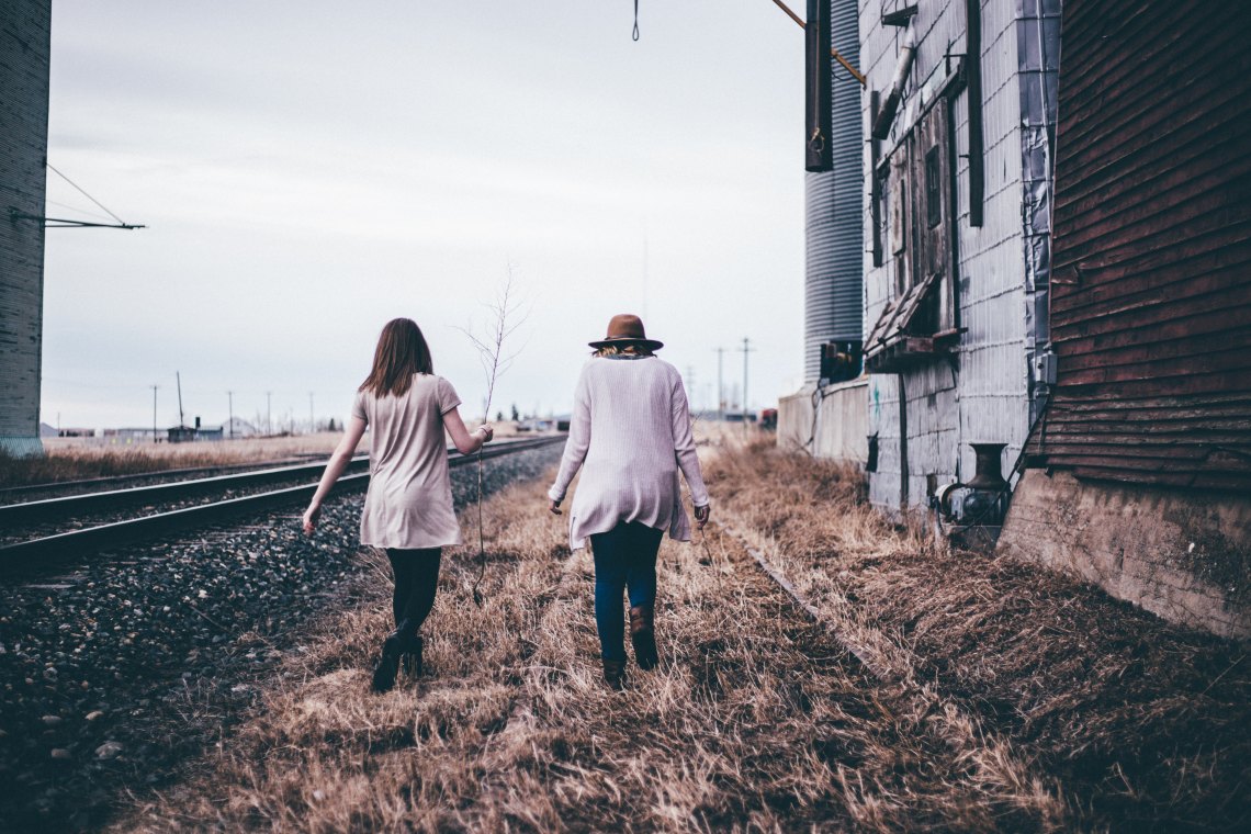 Friends holding hands by railroad track