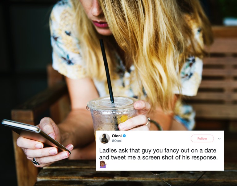 woman looks at her phone while drinking iced coffee