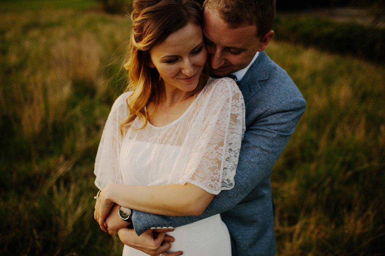 Wedding couple embracing in field