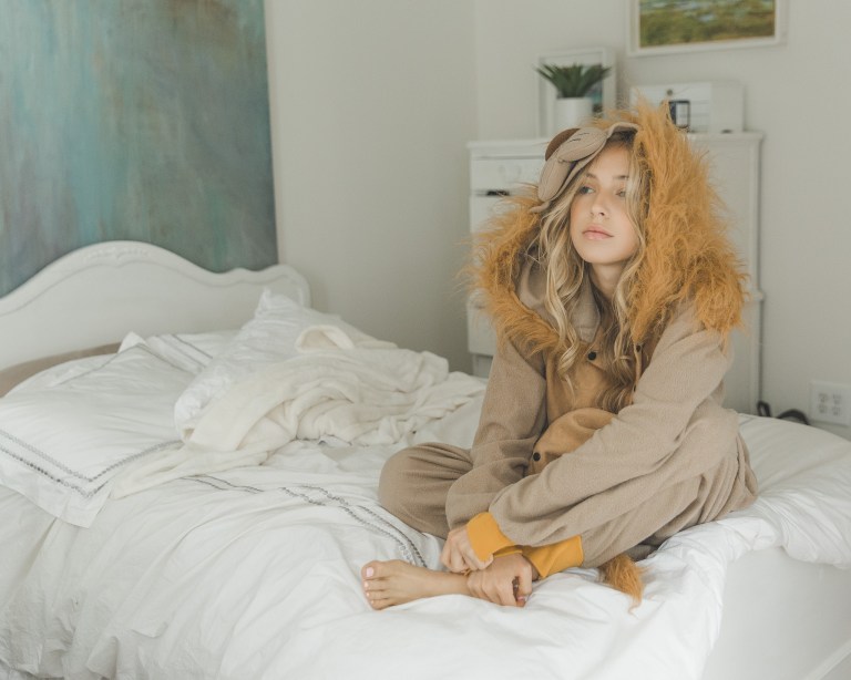 girl in lion onesie sitting on bed