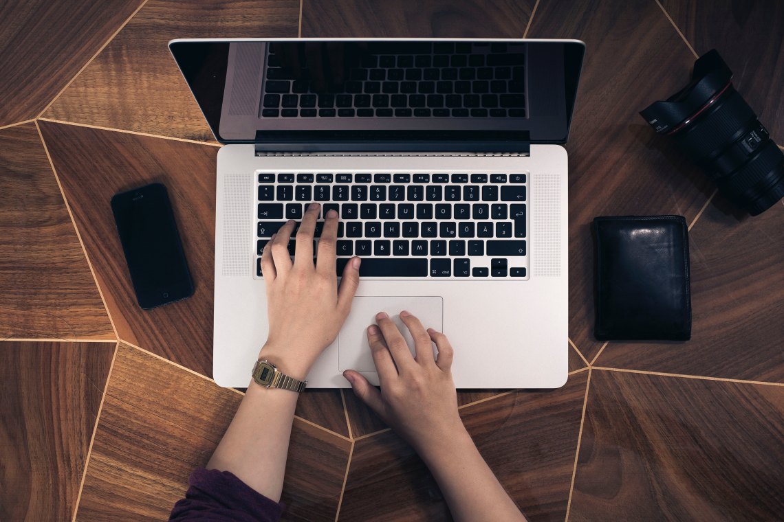 women writing on her macbook laptop