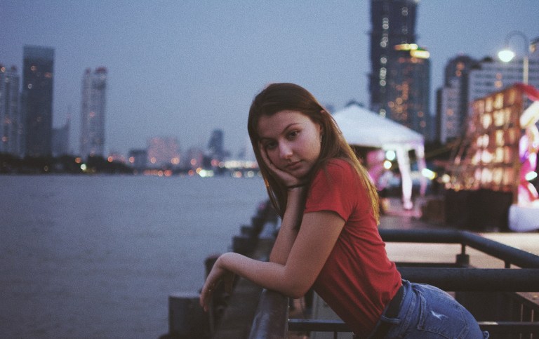 girl sitting by water and city, stop waiting, just go