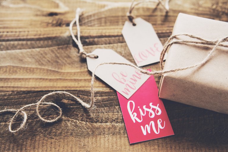 A Christmas gift with tag that say "Kiss Me", "Be Mine" and "Love"