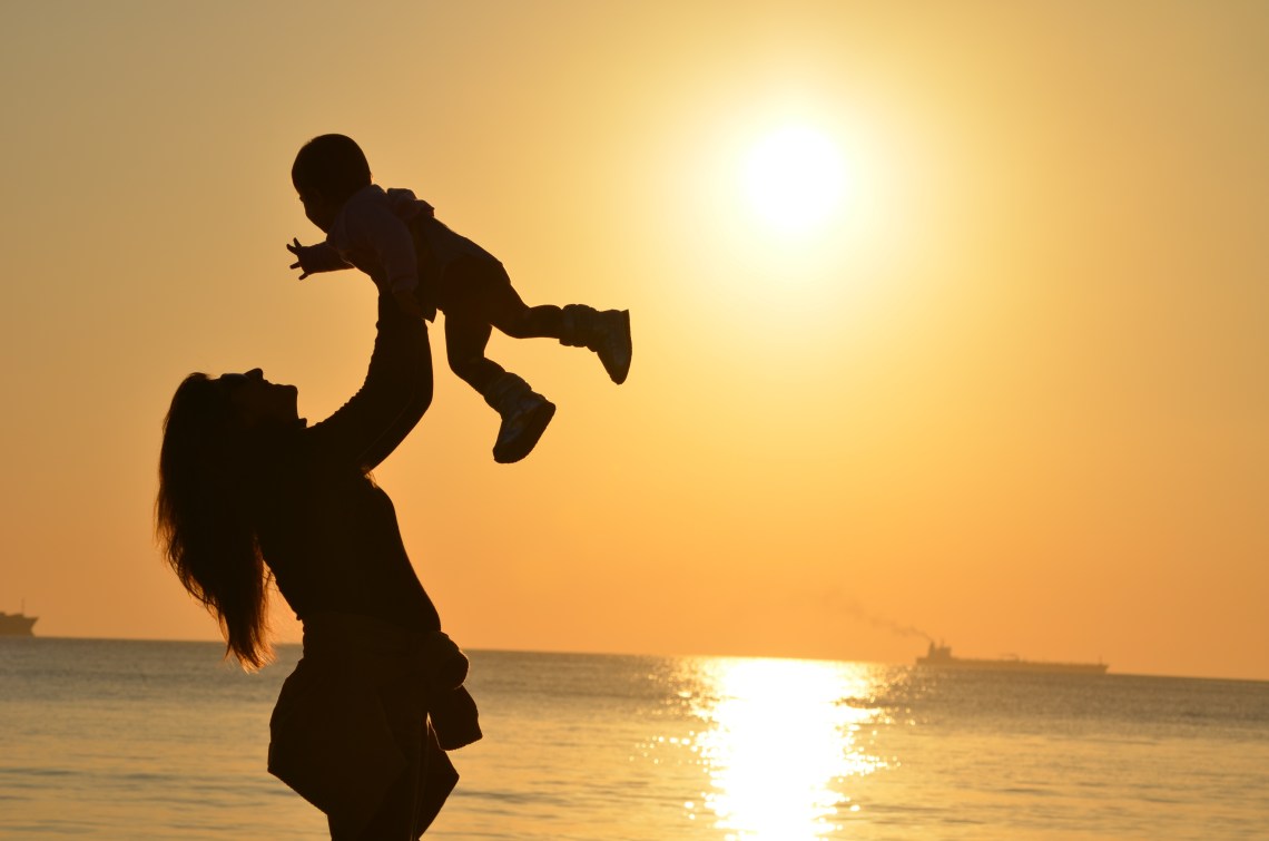 mom holding toddler sunset