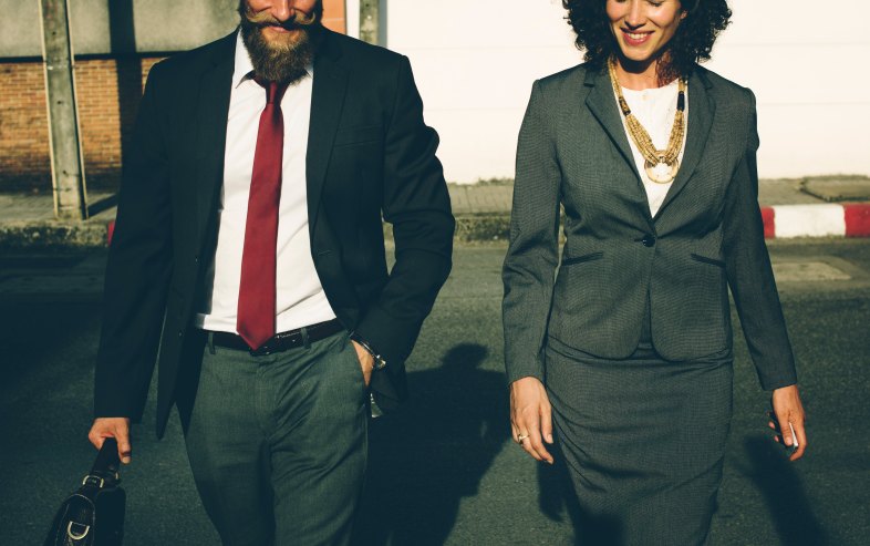 A man and woman in professional attire walk side-by-side