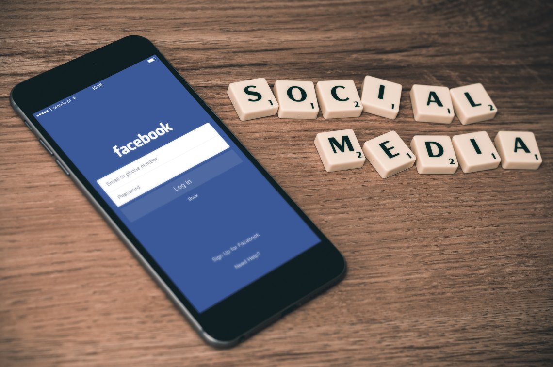 Facebook app on the iPhone and scrabble letters that spell out "social media"
