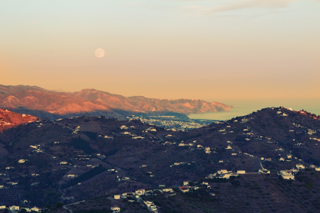 Full moon rises over a rural village overlooking the sea