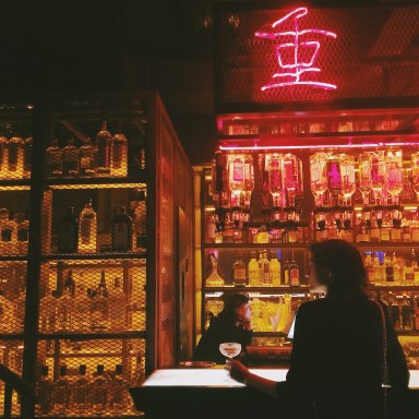 girl standing at a bar and neon signs alone