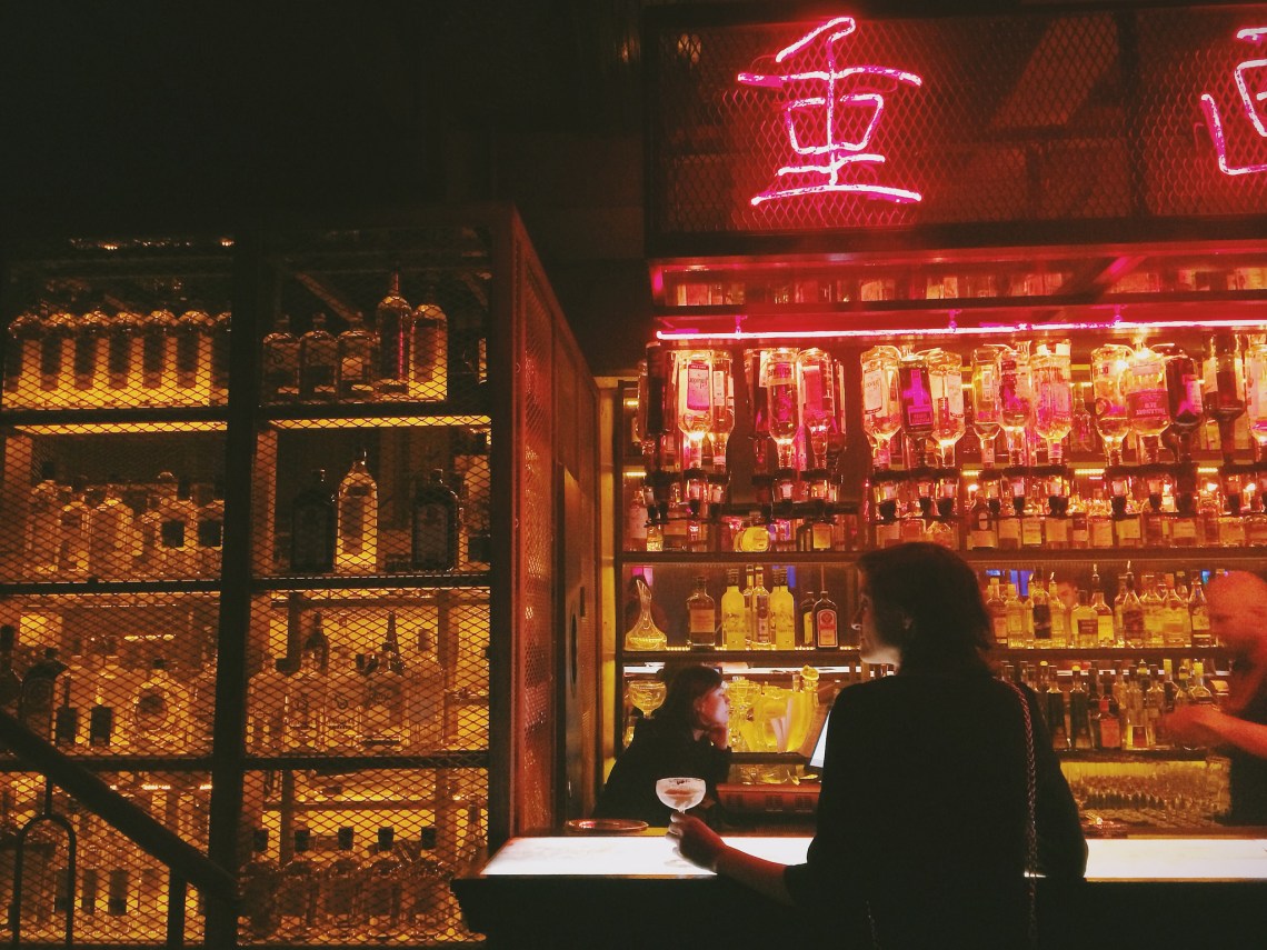 girl standing at a bar and neon signs alone