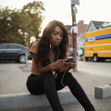 Occupied Young Woman Going Through Her Phone as She Listens to Music